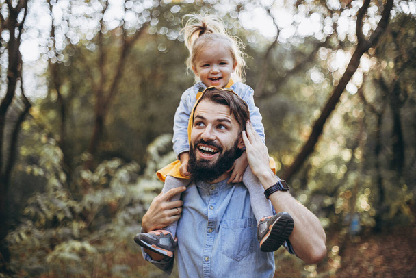 young, stylish bearded father walking with his little daughter in nature at sunset. Family photos of father and one child. selective focus, noise effect - Zdjęcie, obraz