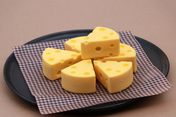 Bolo de queijo feito de chocolate branco em papel escocês marrom na placa redonda preta no chão marrom
. - Foto, Imagem