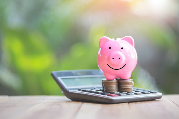 Piggy bank jest umieszczony na monecie i kalkulator. planowanie oszczędności pieniędzy monet na zakup koncepcji domu dla inwestycji w nieruchomości, kredyt hipoteczny i nieruchomości.to zakup domu. - Zdjęcie, obraz