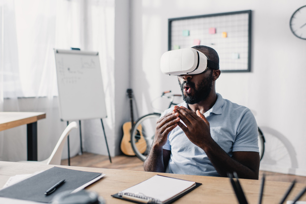 Selective focus of excited african american businessman using vr headset at table in office  - Photo, Image