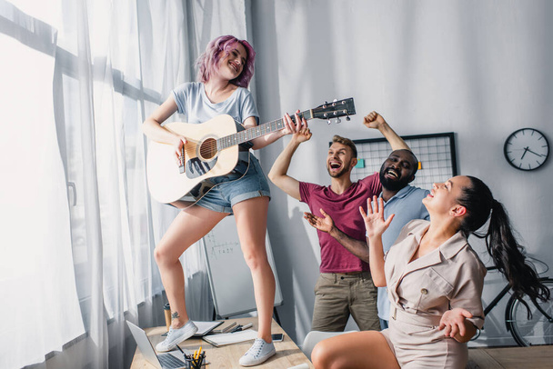 Empresários multiétnicos tocando violão e dançando no escritório
  - Foto, Imagem