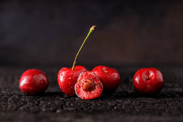 Группа вишни на фоне темного дерева или стол. Сочные свежие вишневые ягоды. Закрытие группы плодов - Фото, изображение