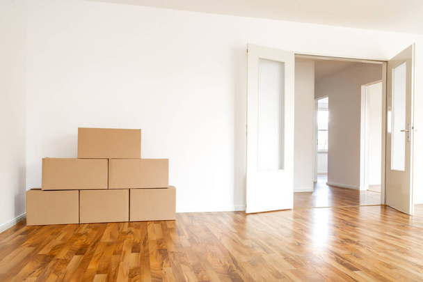 Перемещение коробок в пустой квартире к белой стене - Фото, изображение