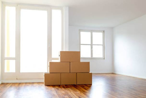 Dobozok mozgatása egy üres lakásban egy fehér falnak támasztva - Fotó, kép