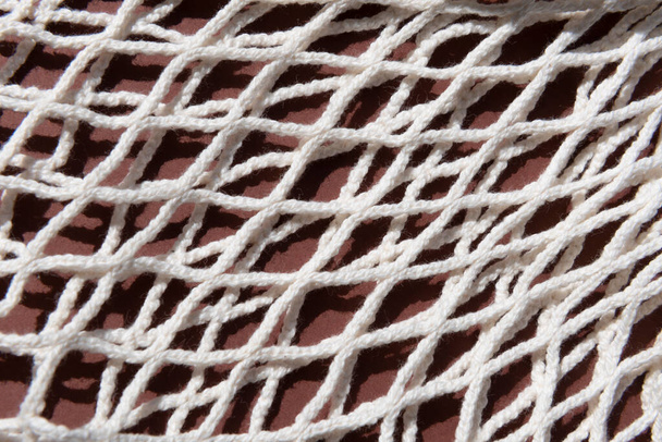 beige mesh zero waste bag close up textuur op een bruine achtergrond - Foto, afbeelding