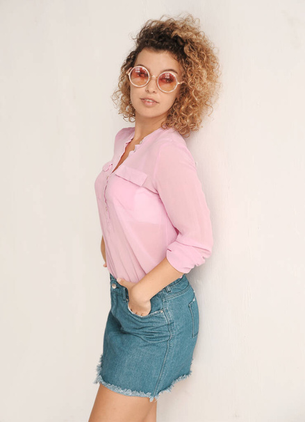 authentic portrait of pretty curly hair woman in sunglasses having fun indoors - Фото, изображение