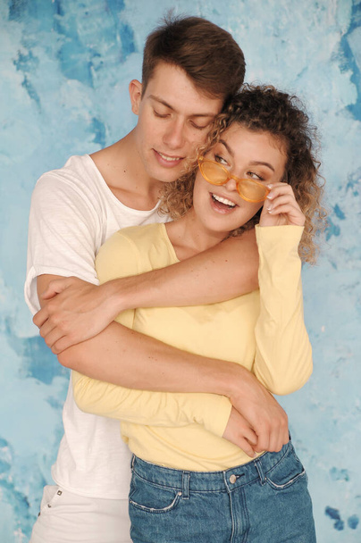 glückliches Paar, das sich in Jeanskleidung auf weißem Hintergrund umarmt. Authentisches Paar hat Spaß im Haus. - Foto, Bild