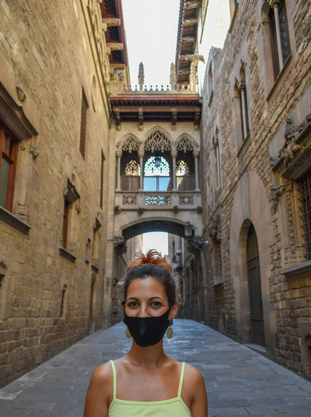 Женщина в хирургической маске, ходит по пустым улицам Барселоны во время коронавируса - Фото, изображение