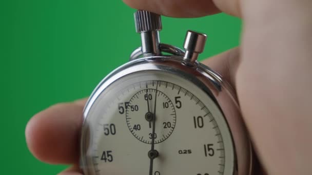 Mão masculina segurando cronômetro analógico na tecla de croma tela verde. O tempo começa com o velho cronômetro homem pressiona botão iniciar no conceito de esporte. Conceito de gestão do tempo
. - Filmagem, Vídeo