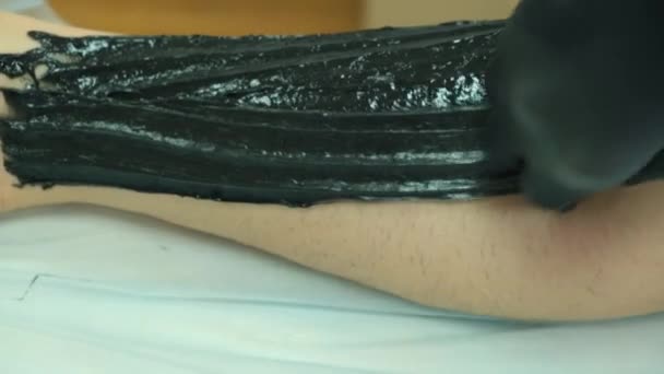 Beelden van een vrouw die suiker maakt op haar been met zwarte pasta - Video