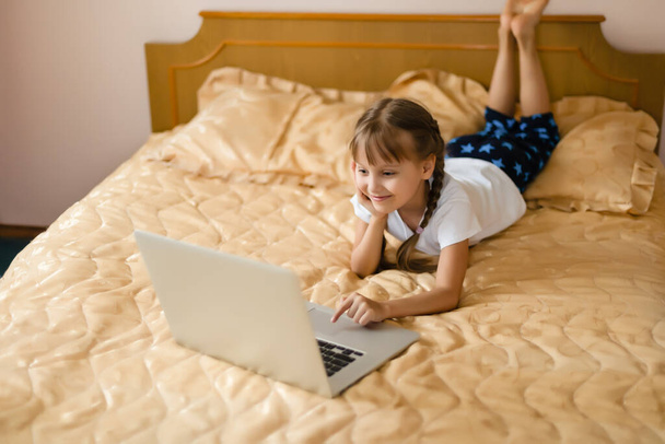 oktatás, szabadidő, technológia és internet koncepció - kis diák lány laptop PC-vel otthon - Fotó, kép