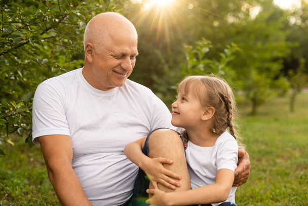 Portrait Of Grandfather With Granddaughter Relaxing Together in the garden - Photo, Image