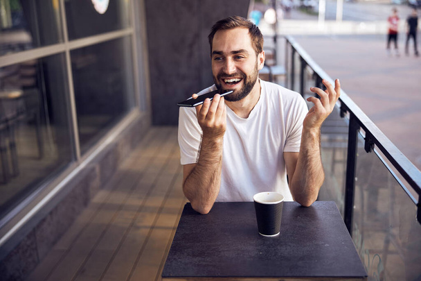 Hombre sentado a la mesa con smartphone y café  - Foto, imagen