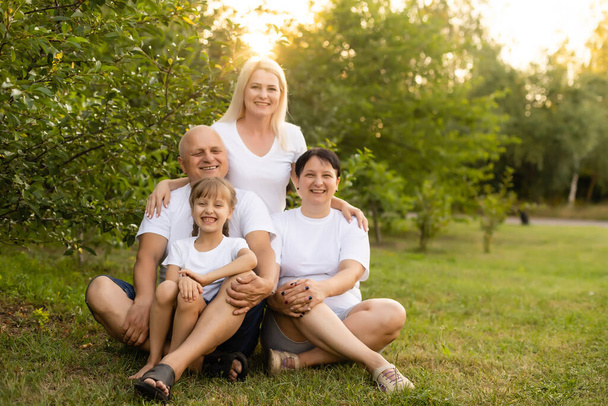 Muotokuva iloinen laajennettu perhe istuu puistossa - Valokuva, kuva