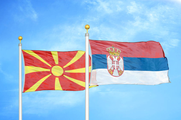 Nord-Mazedonien und Serbien zwei Flaggen auf Fahnenmasten und blauer bewölkter Himmel Hintergrund - Foto, Bild
