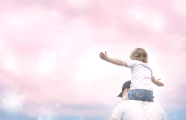 famiglia felice al tramonto rosa. padre e figlia si divertono e giocano nella natura. il bambino siede sulle spalle di suo padre. Foto di alta qualità - Foto, immagini