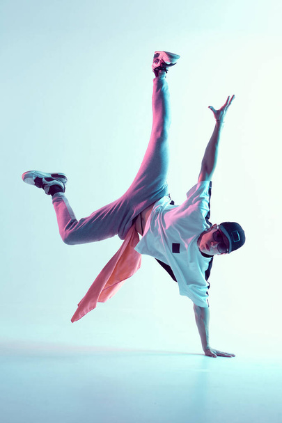 Boy dancing in neon light studio. Acrobatic dancer. Stylish flex. - Фото, изображение