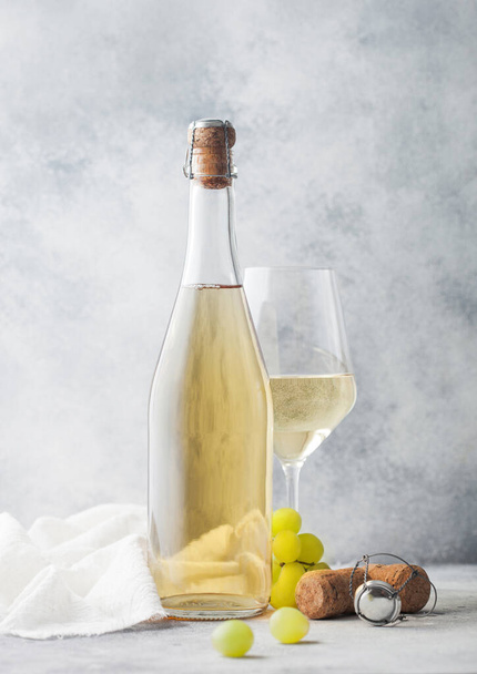 Glass and bottle of white homemade wine with grapes and corkscrew with linen cloth on light table background. - Foto, imagen