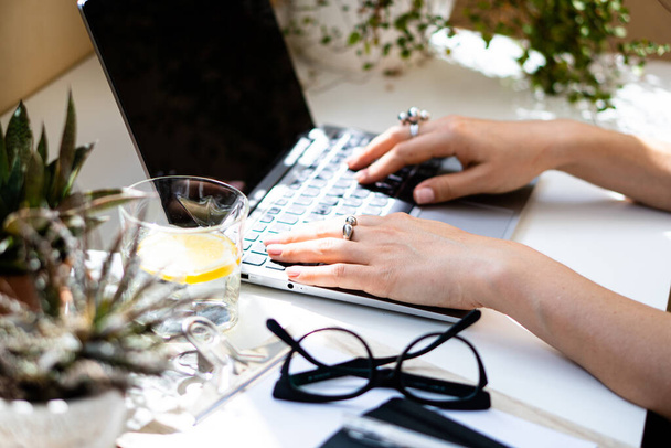 Mãos das mulheres no teclado do laptop, local de trabalho acolhedor
 - Foto, Imagem