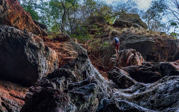 Bela caverna de rocha colorida, árvores verdes, homens subindo, lugar na Tailândia
 - Foto, Imagem