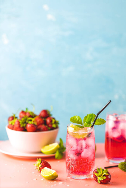 Κοκτέιλ φράουλας μοχίτο με πάγο σε δύο ποτήρια με σταγόνες νερού σε ανοιχτό μπλε χρώμα φόντο, ροζ χαρτόνι. Αντιγραφή χώρου, καλοκαιρινές διακοπές και κόμμα έννοια - Φωτογραφία, εικόνα