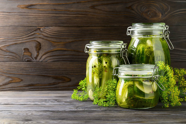 Healthy fermented food. Three glass jars of homemade fermented cucumbers with garlic, dill and pepper. - Photo, Image