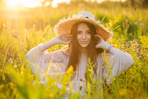 young beautiful european girl in the setting sun, on the field,in hat - Foto, Imagen