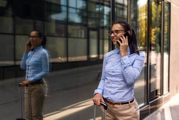 Elfoglalt fiatal nő beszél telefonon és sétál a repülőtéren - Fotó, kép