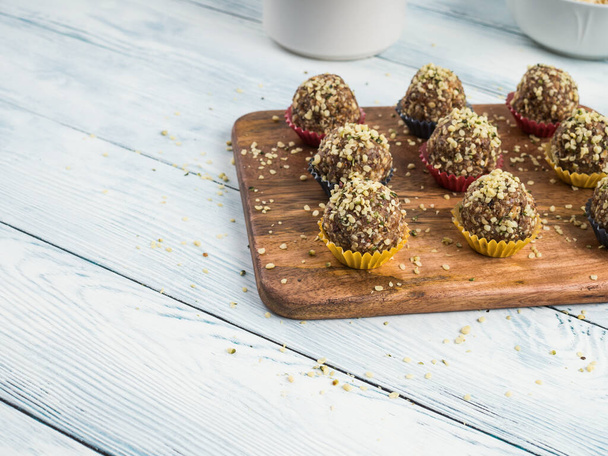 Home made vegan energy protein balls with oats, nuts, dates, dried fruit, flax and hemp seeds, chocolate nibs and maple syrup served in paper cases on wooden board. Copy space - Фото, изображение