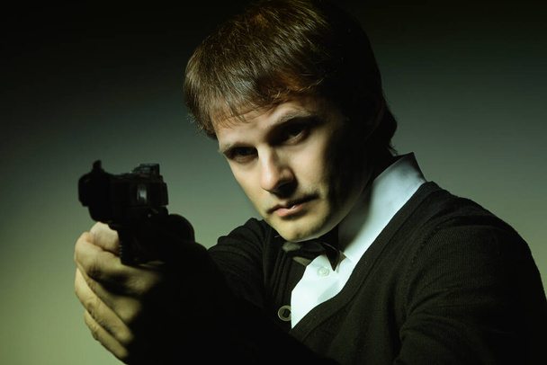 Man portret in het donker met een pistool in zijn hand - Foto, afbeelding
