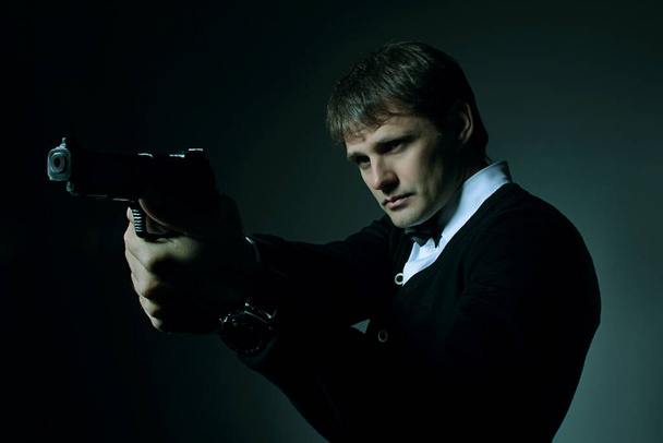 Männerporträt im Dunkeln mit Waffe in der Hand - Foto, Bild