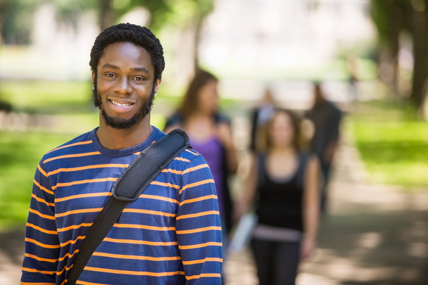 junger männlicher Student lächelt auf dem Campus - Foto, Bild