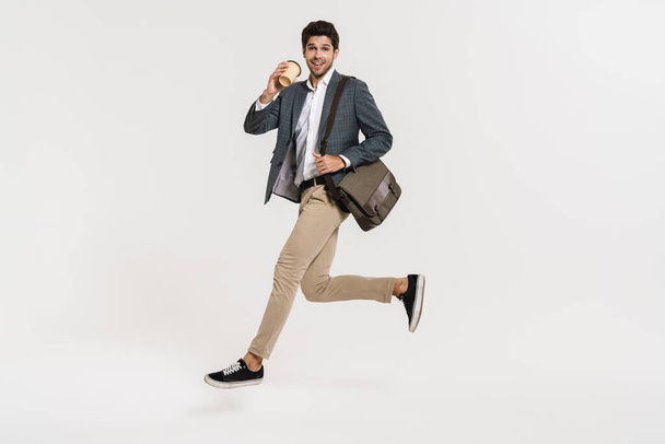 Photo of cheerful caucasian businessman drinking coffee while running with bag isolated over white wall - Фото, зображення