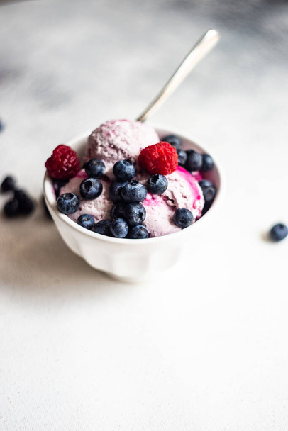 Φρούτα καλοκαιρινό παγωτό επιδόρπιο με φρέσκα βιολογικά μούρα του blueberry σερβίρεται σε μπολ σε πέτρινο φόντο με αντίγραφο χώρο - Φωτογραφία, εικόνα
