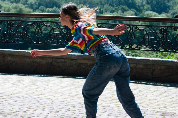 Attractive teenage girl quickly rides around the city on roller skates on sunny summer day - Photo, image