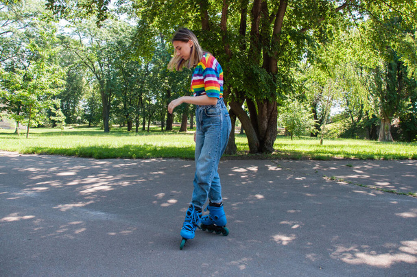 Beautiful teenager girl has fun rollerblading in the park, performs tricks. - Foto, Imagem