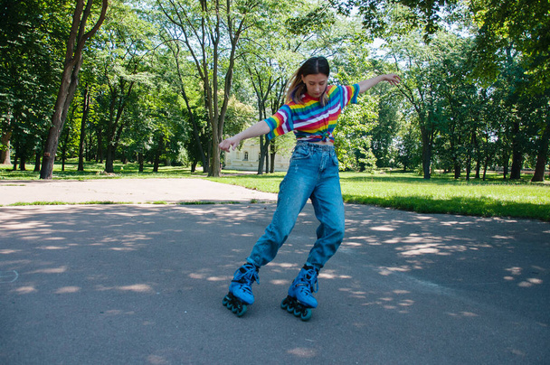 Beautiful teenager girl has fun rollerblading in the park, performs tricks. - Photo, image