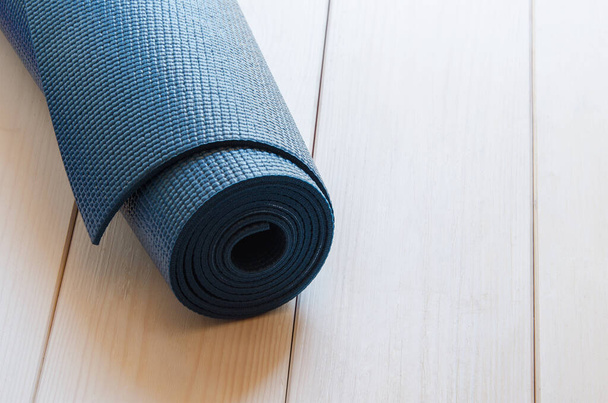 Tapis bleu foncé pour yoga, pilates ou fitness sur fond bois. Espace pour le texte. Style vintage. - Photo, image