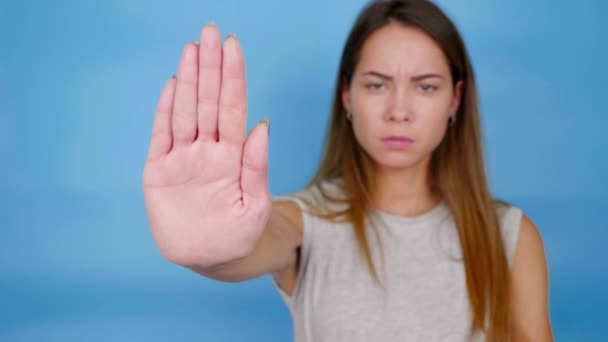 Grave donna arrabbiata in grigio T-shirt tiene fuori il palmo della mano alla fotocamera, dice stop - Filmati, video