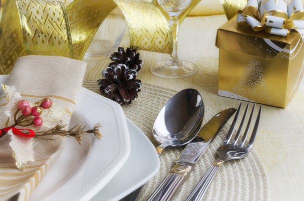 Όμορφη διακόσμηση για εορταστικό δείπνο. Χριστουγεννιάτικες ρυθμίσεις τραπεζιού σε χρυσό τόνο: μαχαιροπήρουνα με πετσέτα σε λινό τραπεζομάντιλο. Χειμερινές διακοπές. Καλά Χριστούγεννα ή Καλή Χρονιά έννοια. - Φωτογραφία, εικόνα