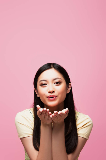 young asian woman sending air kiss and looking at camera isolated on pink  - Fotografie, Obrázek