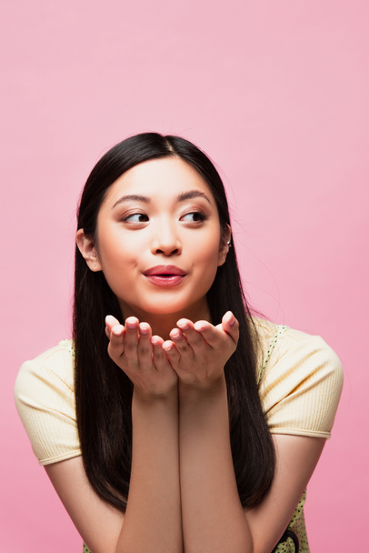 young asian woman sending air kiss and looking away isolated on pink  - Foto, afbeelding