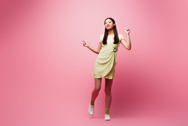 cheerful asian girl in dress dancing on pink  - Foto, Imagem