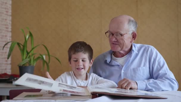 momentos felices, pequeño niño feliz con su abuelo alegre tiene recuerdos familiares, viendo álbum de fotos - Metraje, vídeo