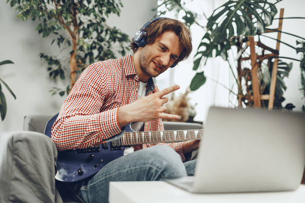 Man playing electric guitar and recording music into laptop - Photo, Image