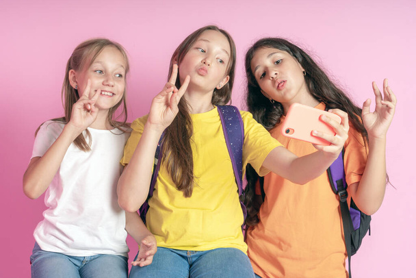 Tres chicas adolescentes sonriendo y filma un video sobre un fondo rosa. Selfies. - Foto, imagen