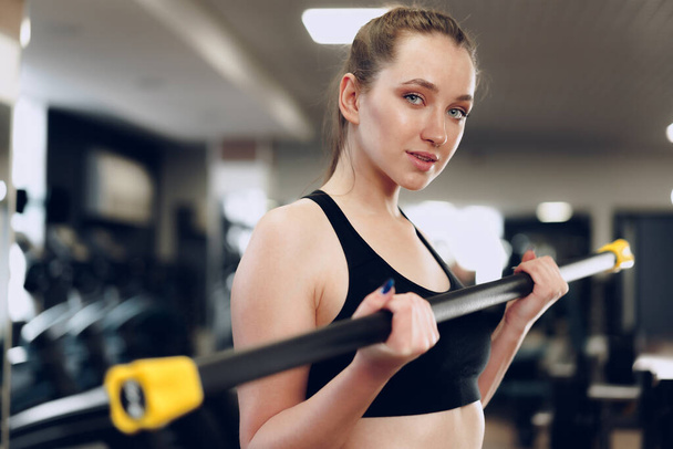 Young brunette sporty woman exercising with dumbbell in a gym - Photo, Image