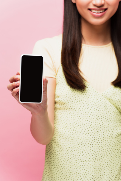 vue recadrée de femme positive tenant smartphone avec écran blanc isolé sur rose  - Photo, image