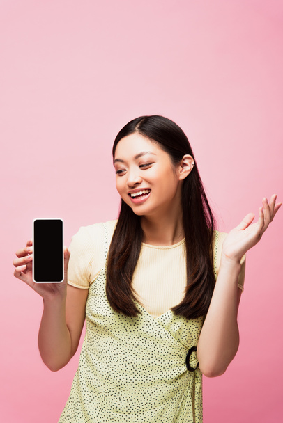 excited asian woman looking at smartphone with blank screen isolated on pink  - Φωτογραφία, εικόνα