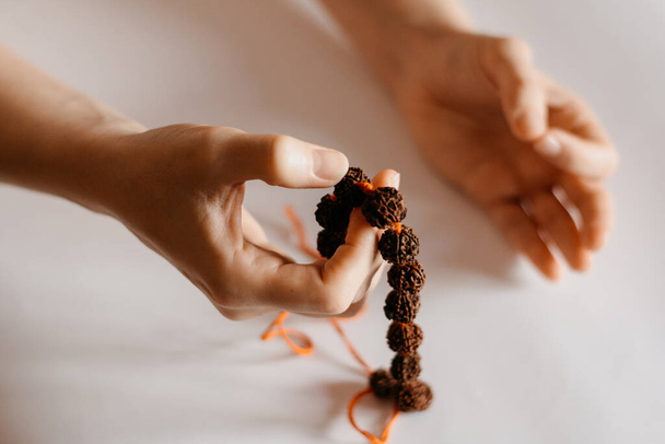 Rudraksha collana di perline in mano di preghiera femminile, primo piano - Foto, immagini